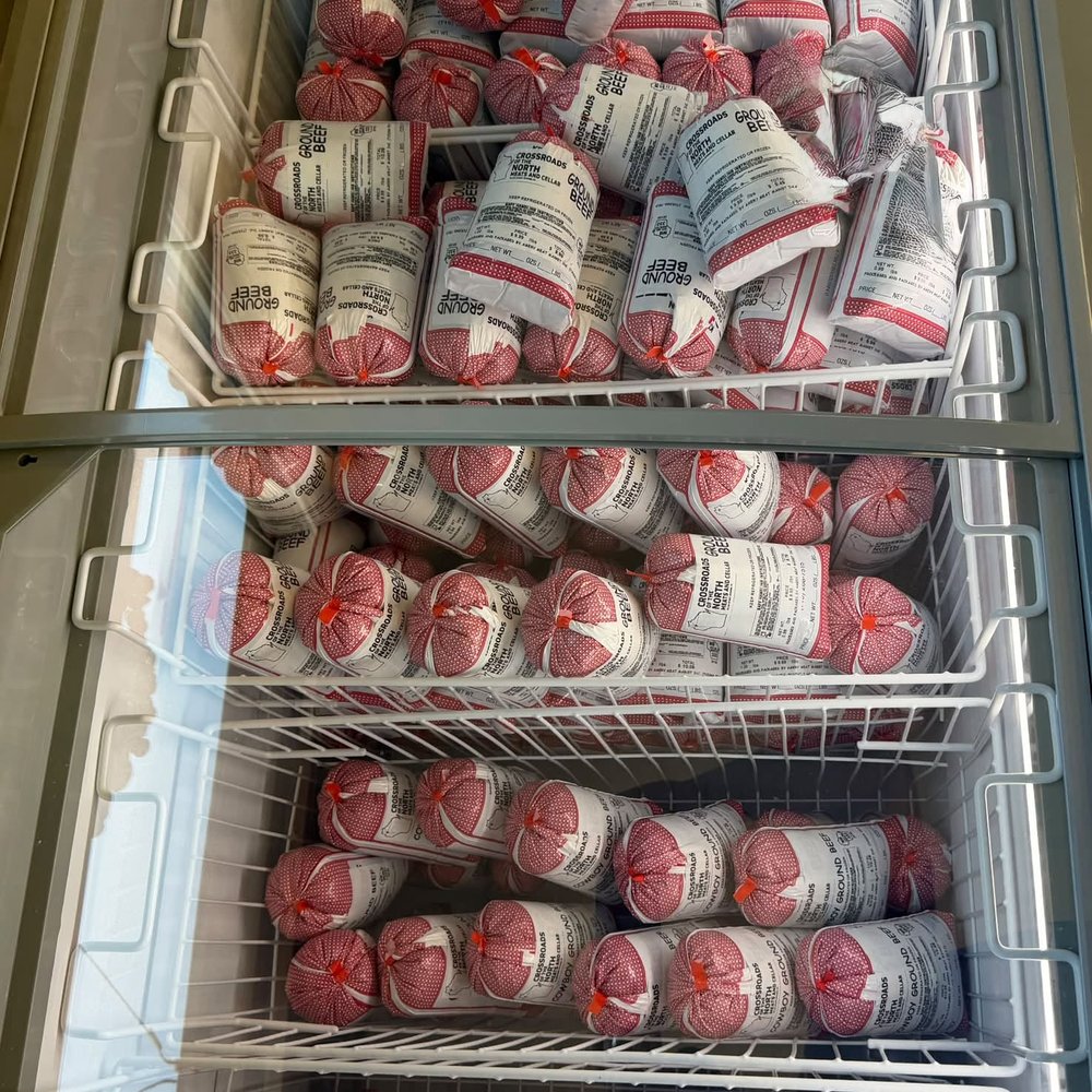 Crossroads freezer stocked with vacuum-sealed ground beef rolls in branded packaging — freezer beef packages ready for the cabin