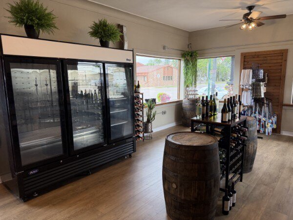 Curated wine and spirits display against a dark wall — bottles, glassware, and decorative greenery