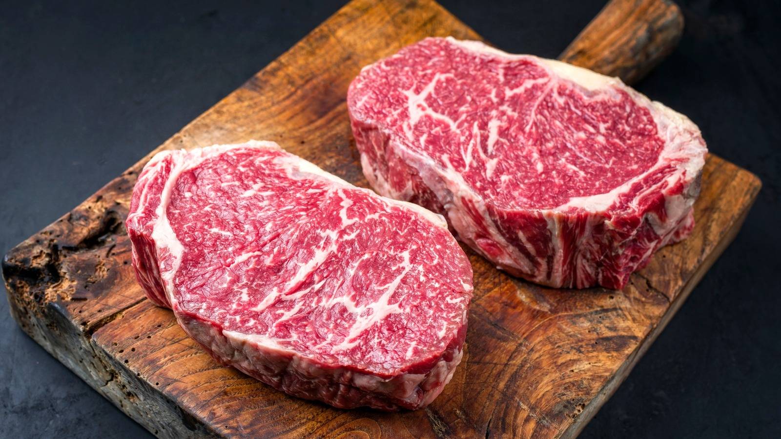 Hand-cut ribeye steaks on a rustic cutting board